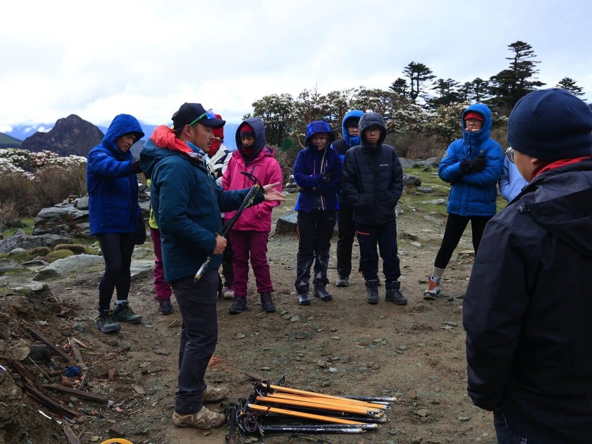 A guide briefing the group, ice axes laid out on the ground
