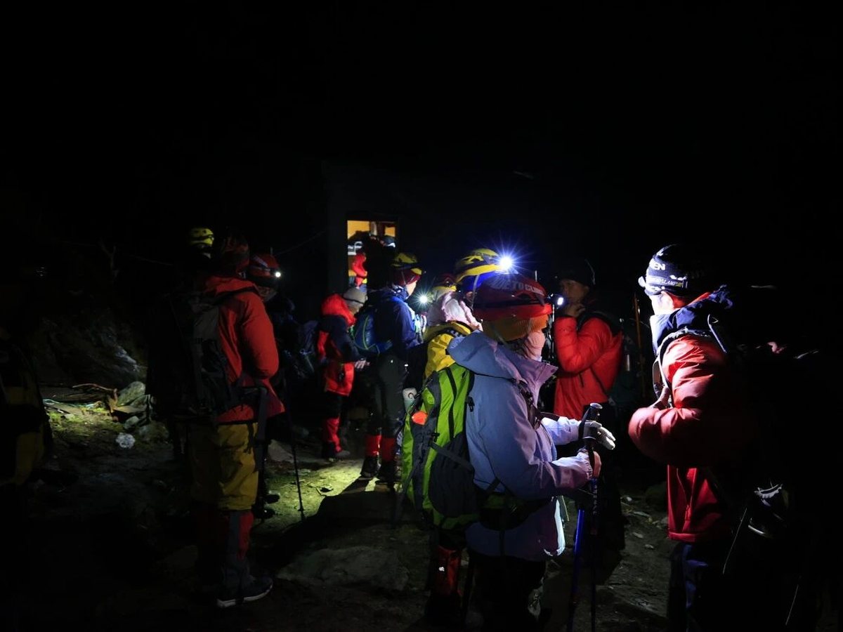Hikers with head torches gathering before an alpine start